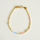 Jasna, delikatna bransoletka z koralików z pozłacanym zapięciem.